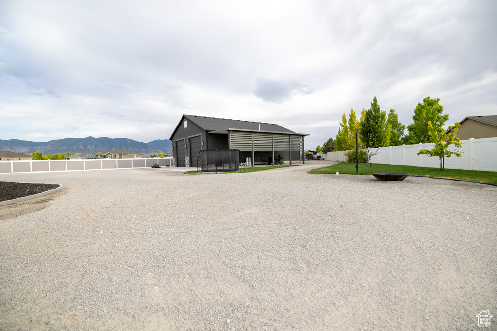 View of side of home featuring a mountain view, a detached garage, and an outbuilding