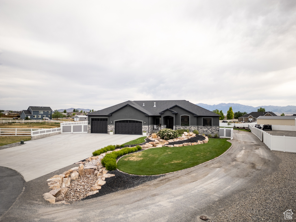 Ranch-style house with driveway, a garage, a mountain view, stone siding, and stucco siding