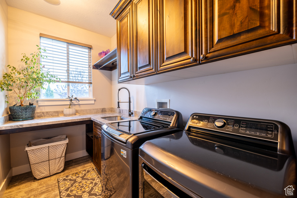 Laundry room with independent washer and dryer, cabinet space, and light wood-type flooring