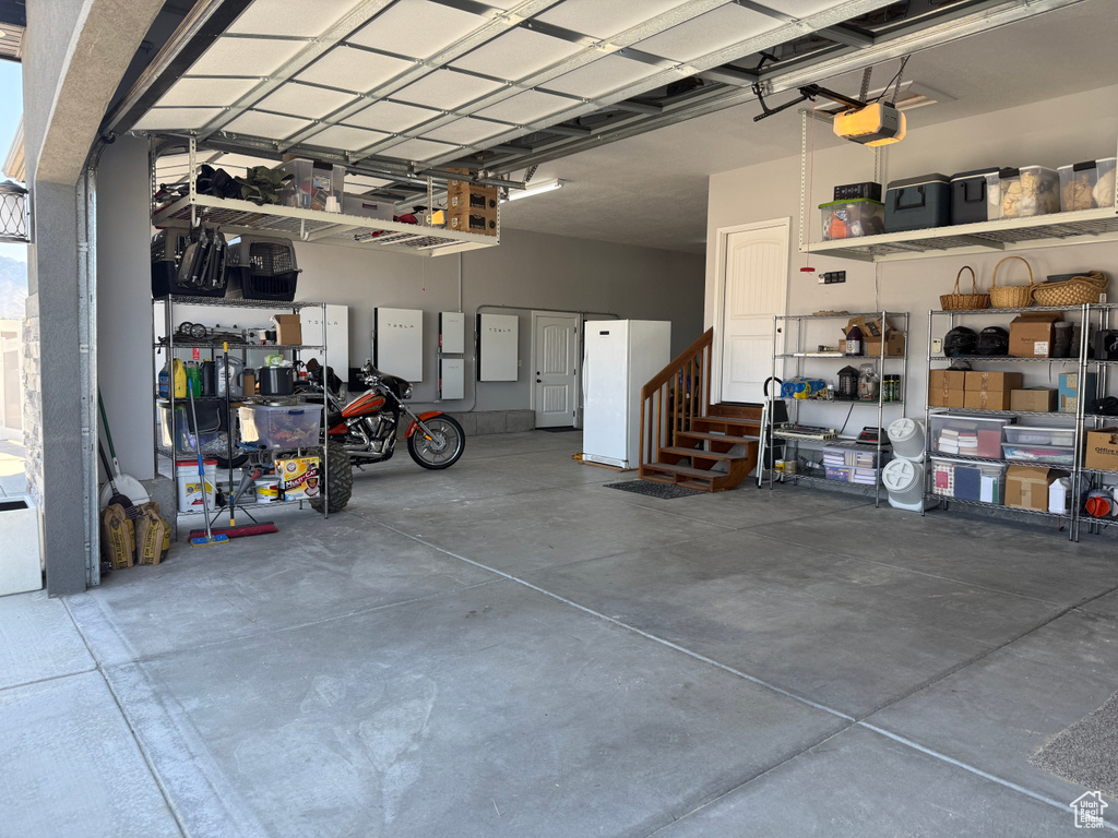 Garage featuring freestanding refrigerator and a garage door opener