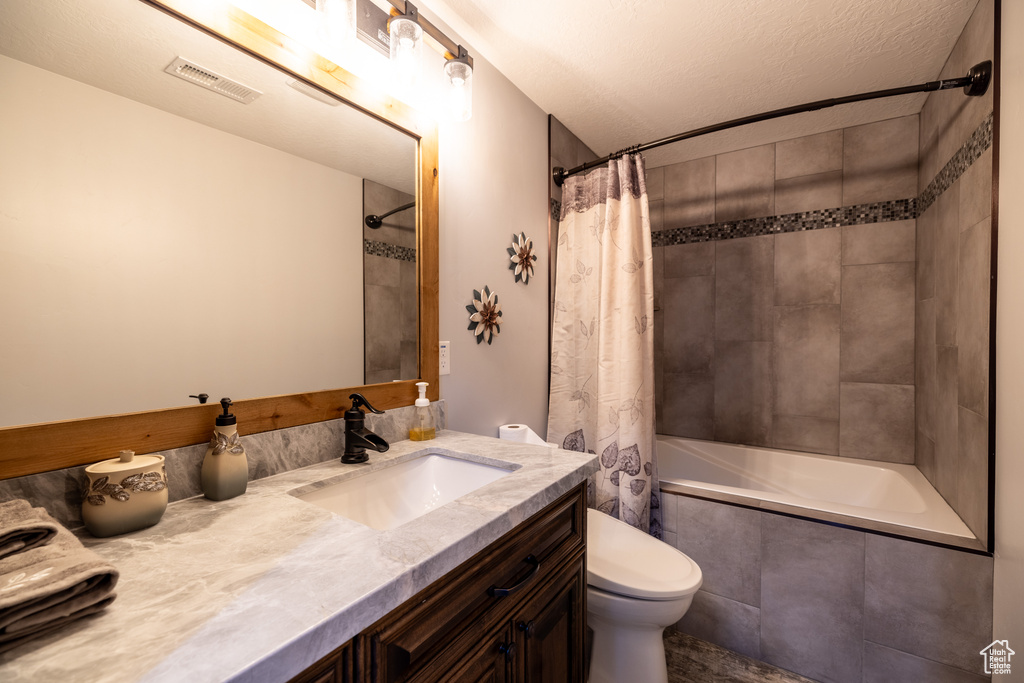 Full bath featuring vanity, tiled shower / bath combo, and a textured ceiling