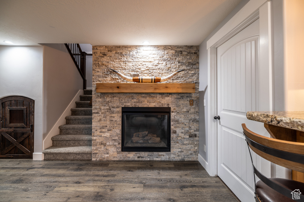 Living room featuring a stone fireplace, wood finished floors, stairway, and recessed lighting