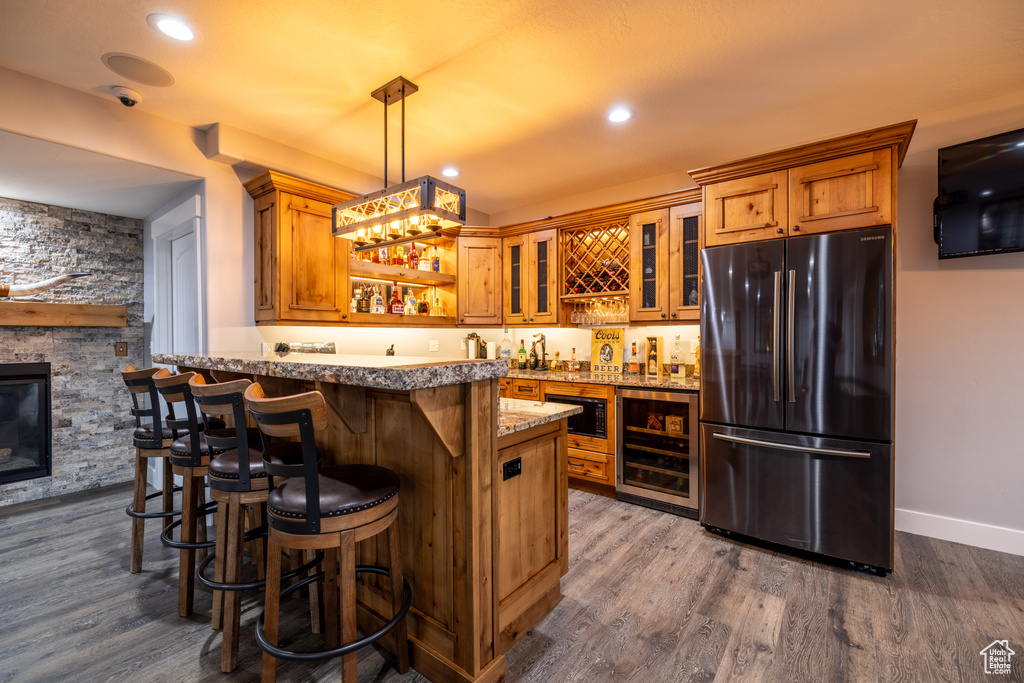 Indoor wet bar with freestanding refrigerator, wine cooler, dark wood-style flooring, hanging light fixtures, and black microwave