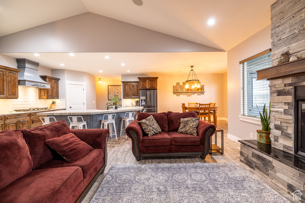 Living area with lofted ceiling, a chandelier, light wood-style floors, and recessed lighting