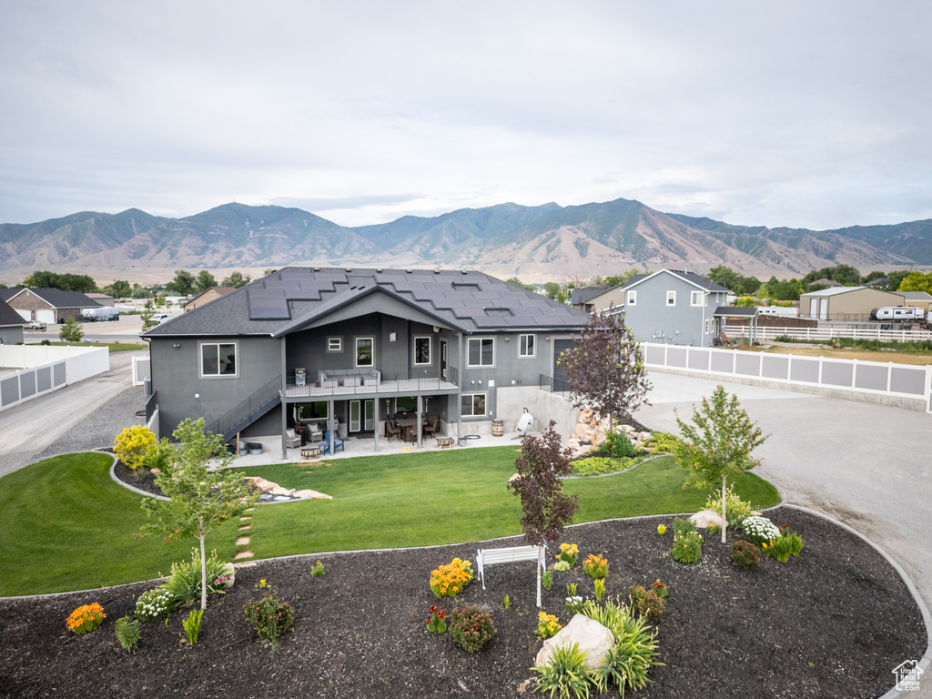 Rear view of property with stairs, a patio area, a fenced backyard, roof mounted solar panels, and a deck with mountain view