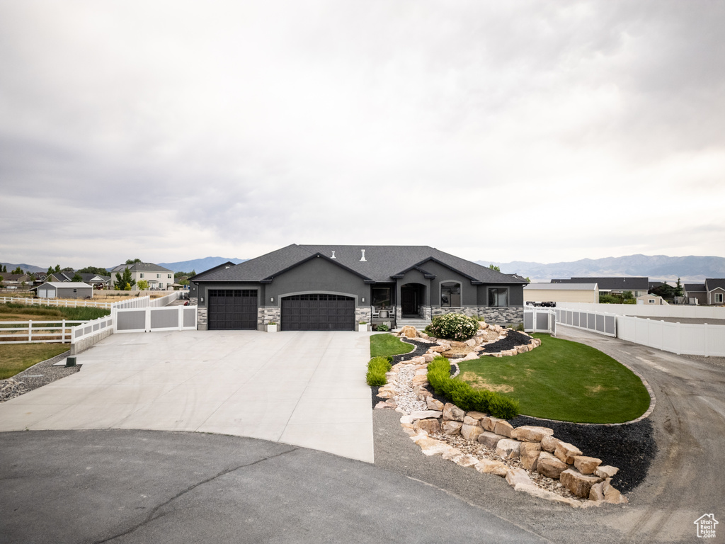 View of front of property with an attached garage, driveway, a mountain view, and stone siding
