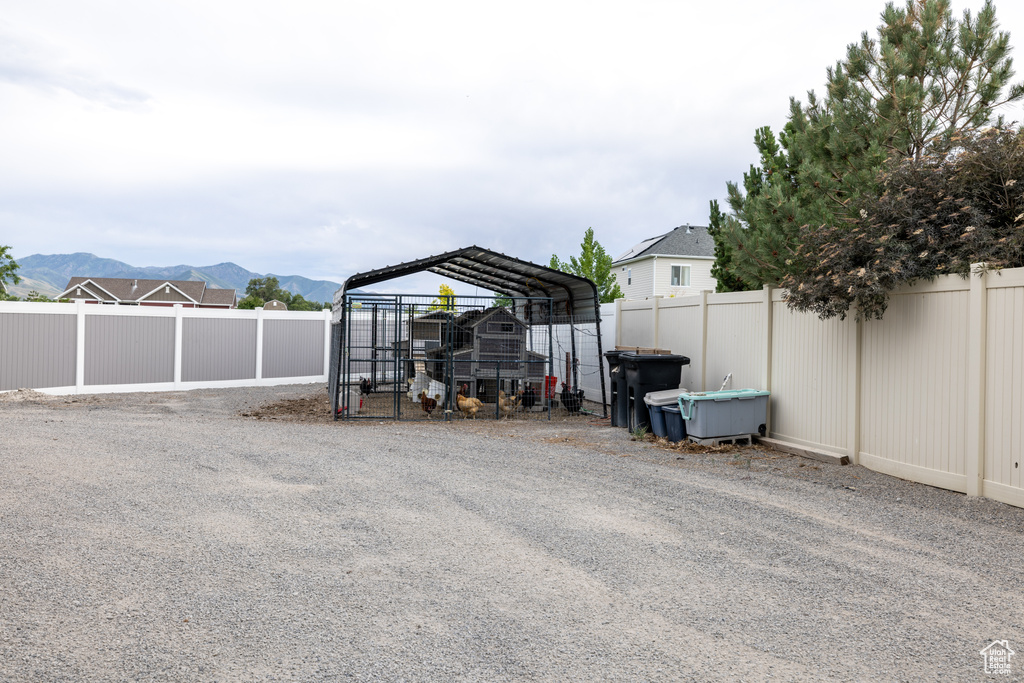 View of car parking with a fenced backyard, a mountain view, a detached carport, and exterior structure