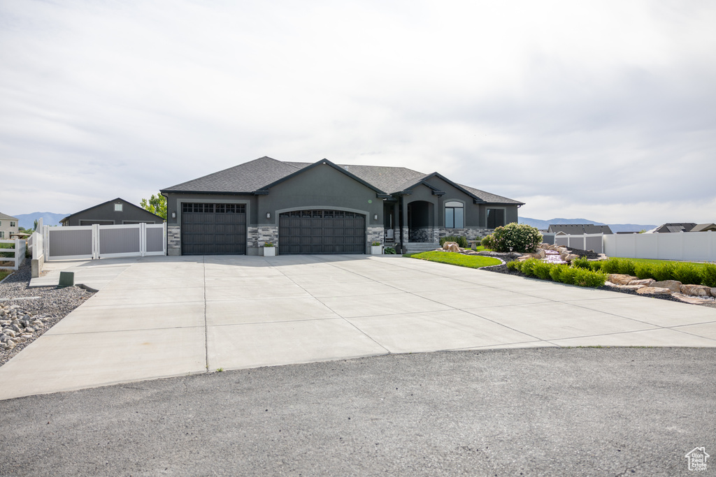 View of front facade with an attached garage, driveway, stucco siding, and stone siding