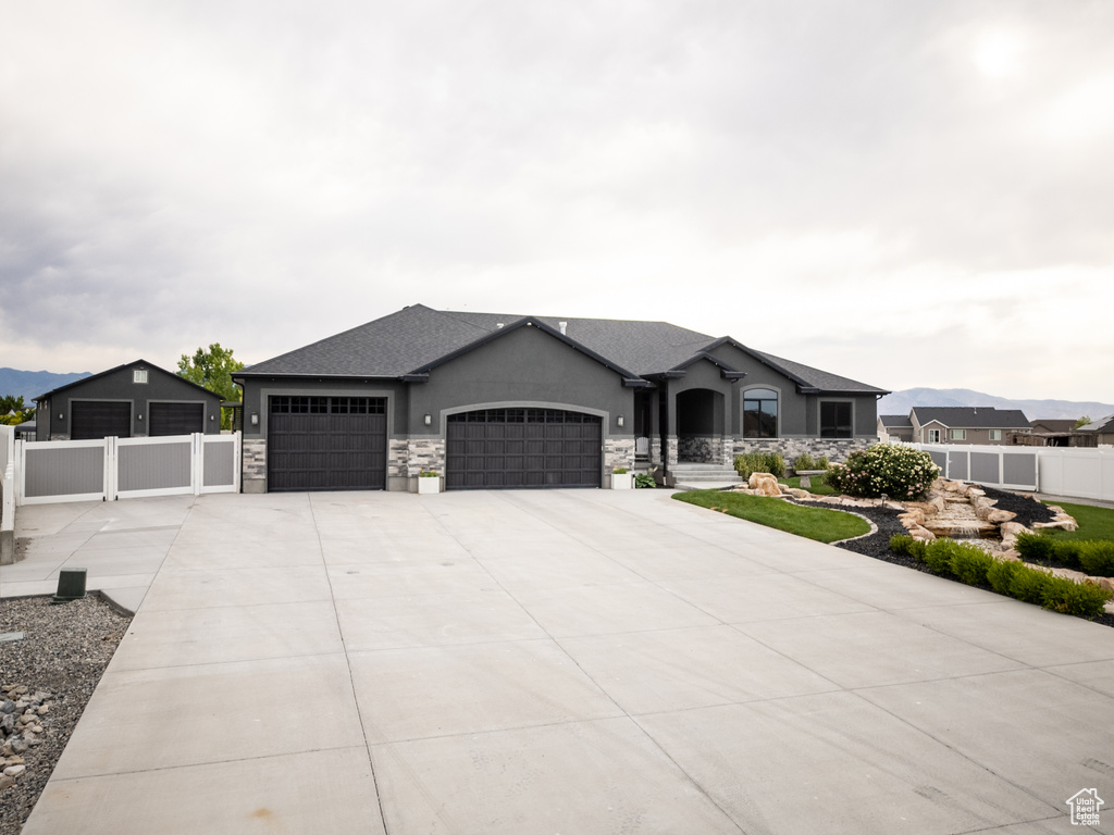 French country home with an attached garage, driveway, stucco siding, and stone siding