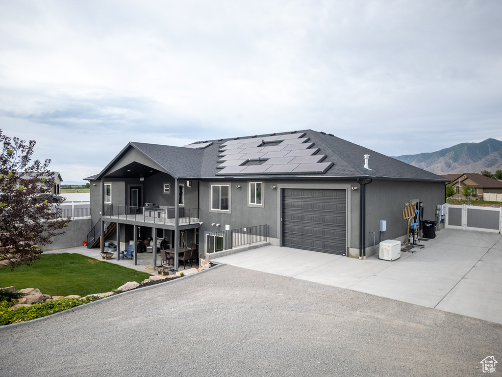 View of front of house featuring a garage, solar panels, driveway, stairway, and roof with shingles