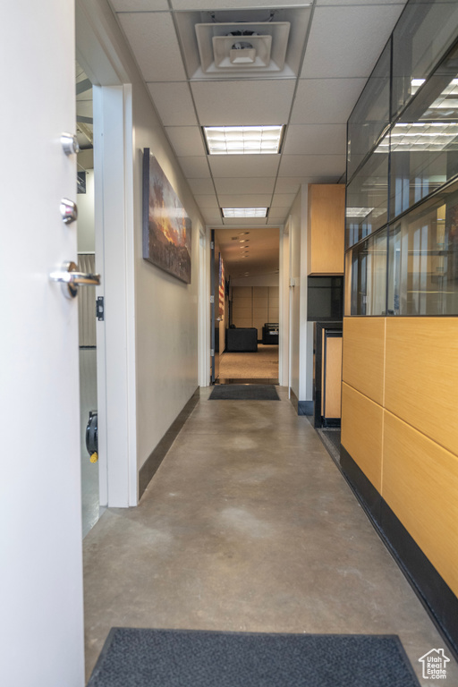 Hall with finished concrete flooring and a paneled ceiling