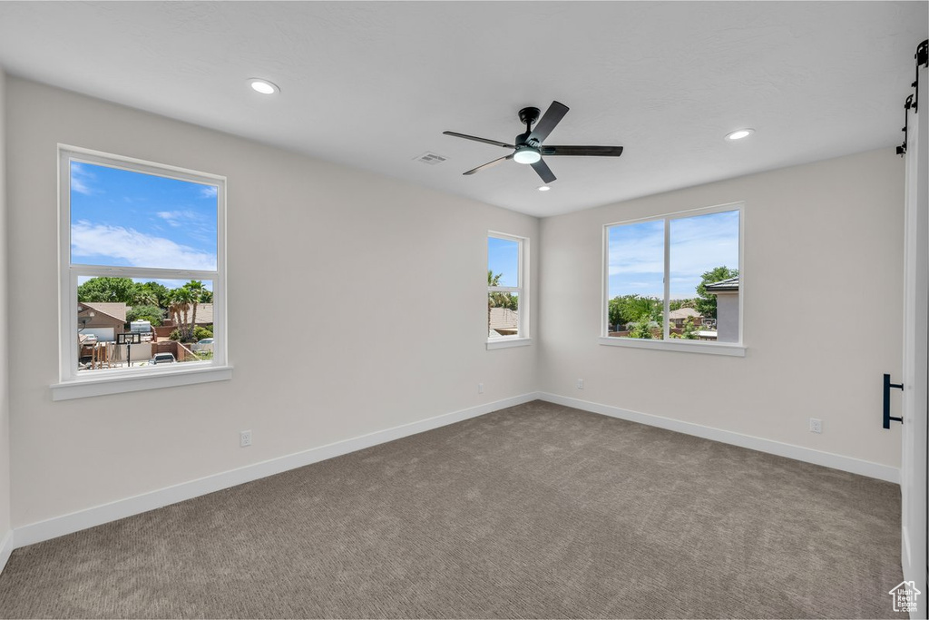 Unfurnished room with a barn door, carpet flooring, recessed lighting, and a ceiling fan