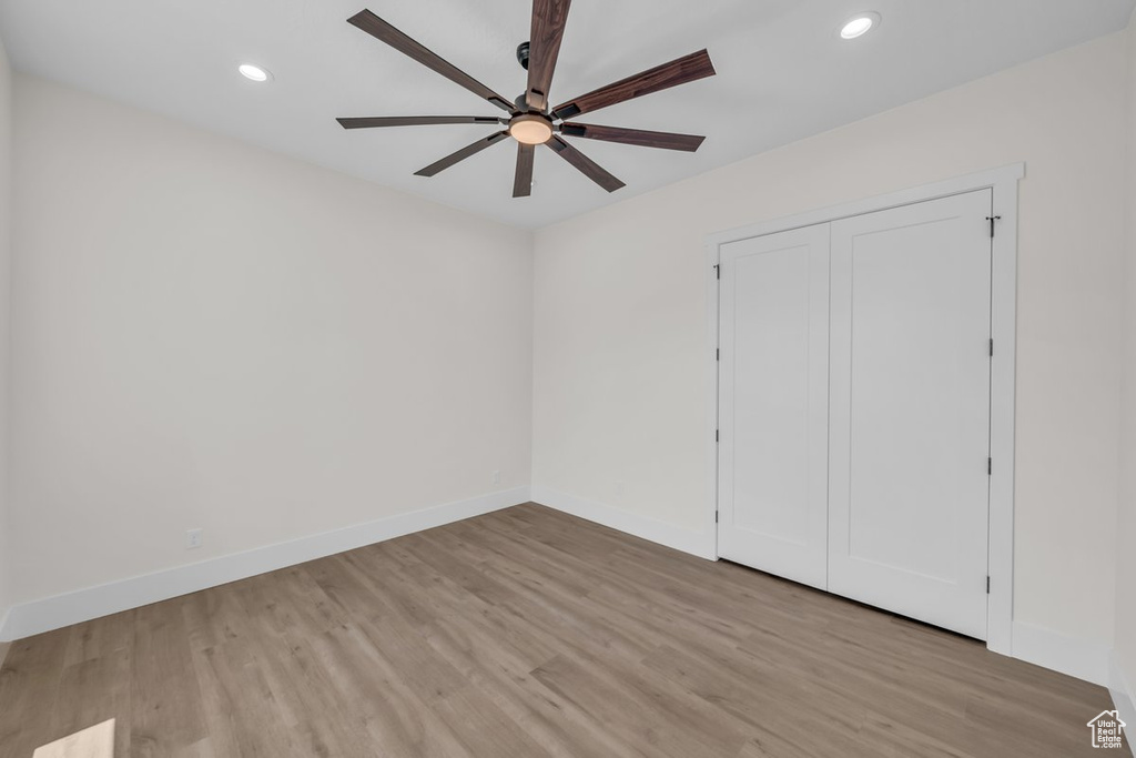 Unfurnished bedroom featuring wood finished floors, recessed lighting, ceiling fan, and a closet