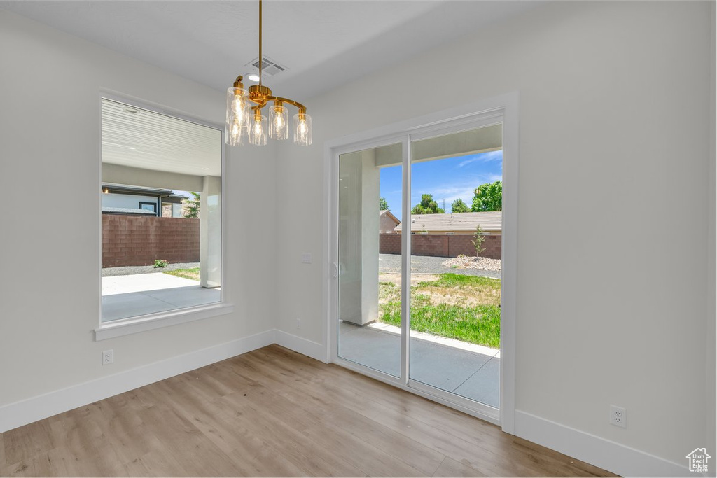 Unfurnished dining area featuring a chandelier and wood finished floors