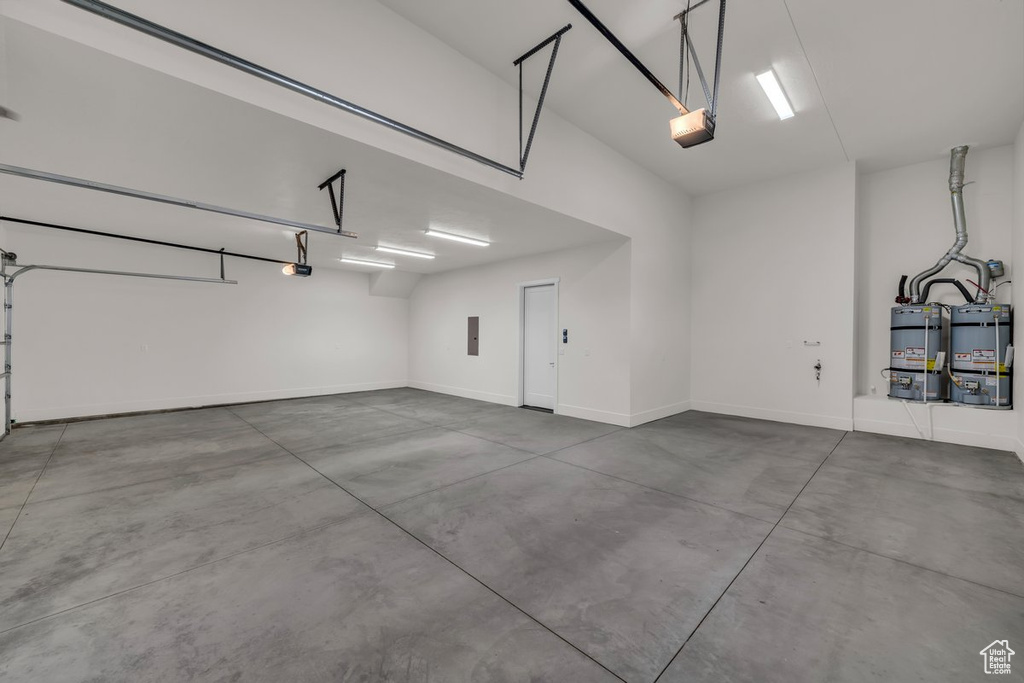 Garage featuring water heater, a garage door opener, and electric panel
