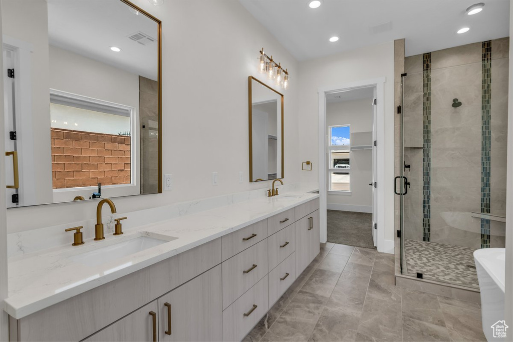 Bathroom with double vanity, a shower stall, a freestanding tub, recessed lighting, and marble finish flooring