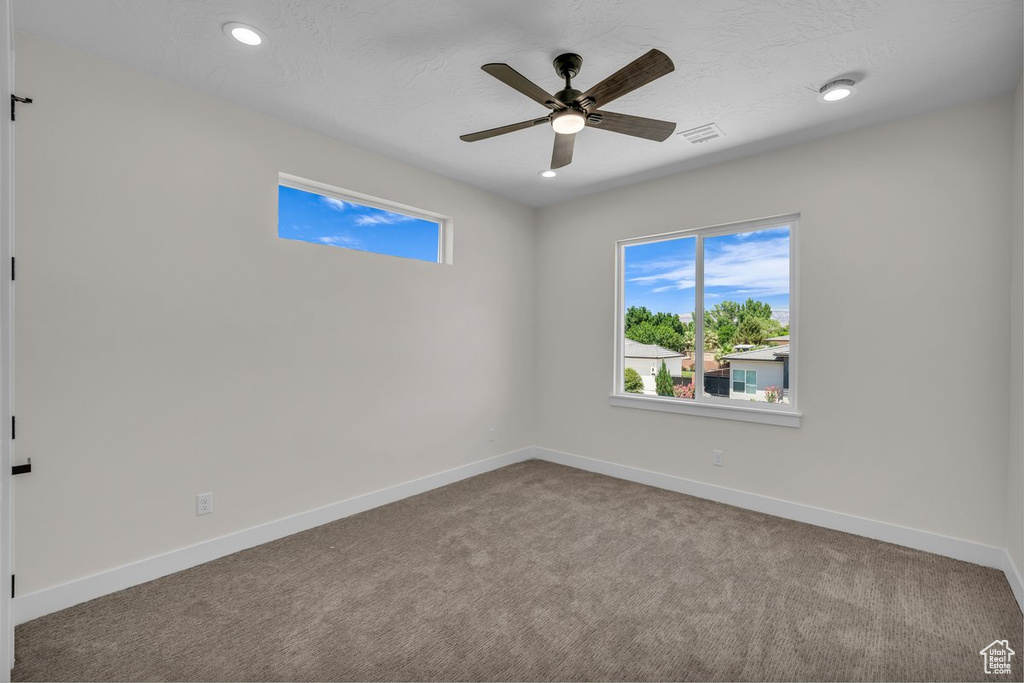 Carpeted spare room with healthy amount of natural light, ceiling fan, and recessed lighting