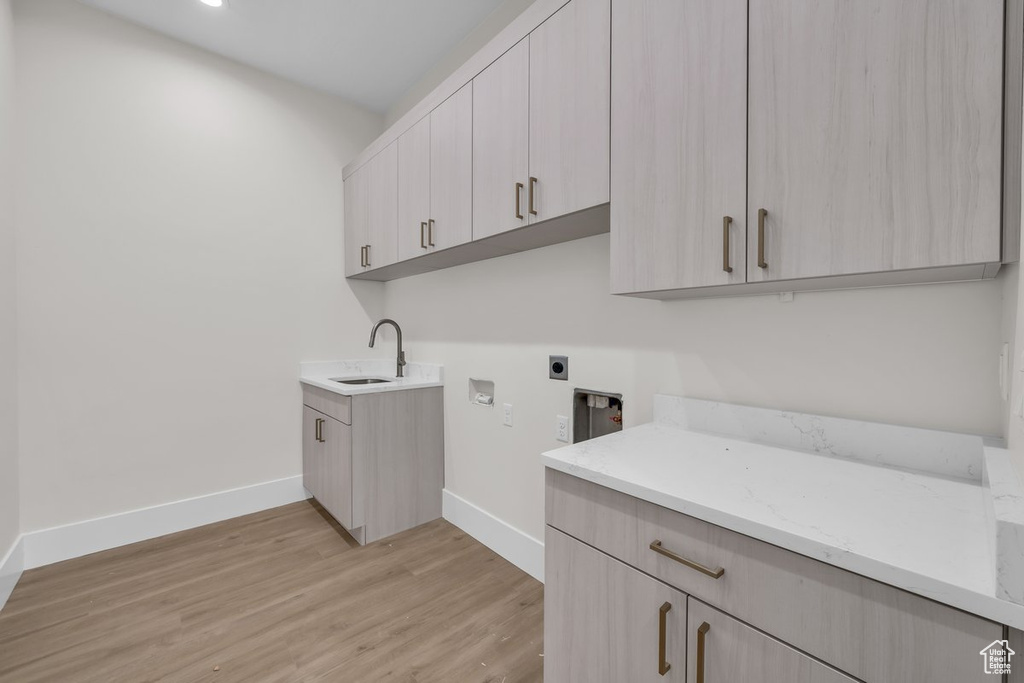 Laundry room with electric dryer hookup, washer hookup, light wood-style floors, and cabinet space