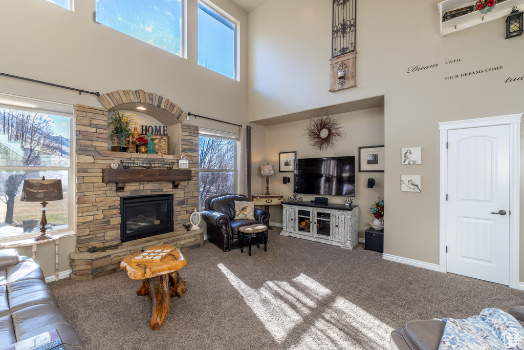 Carpeted living area with a stone fireplace and a towering ceiling