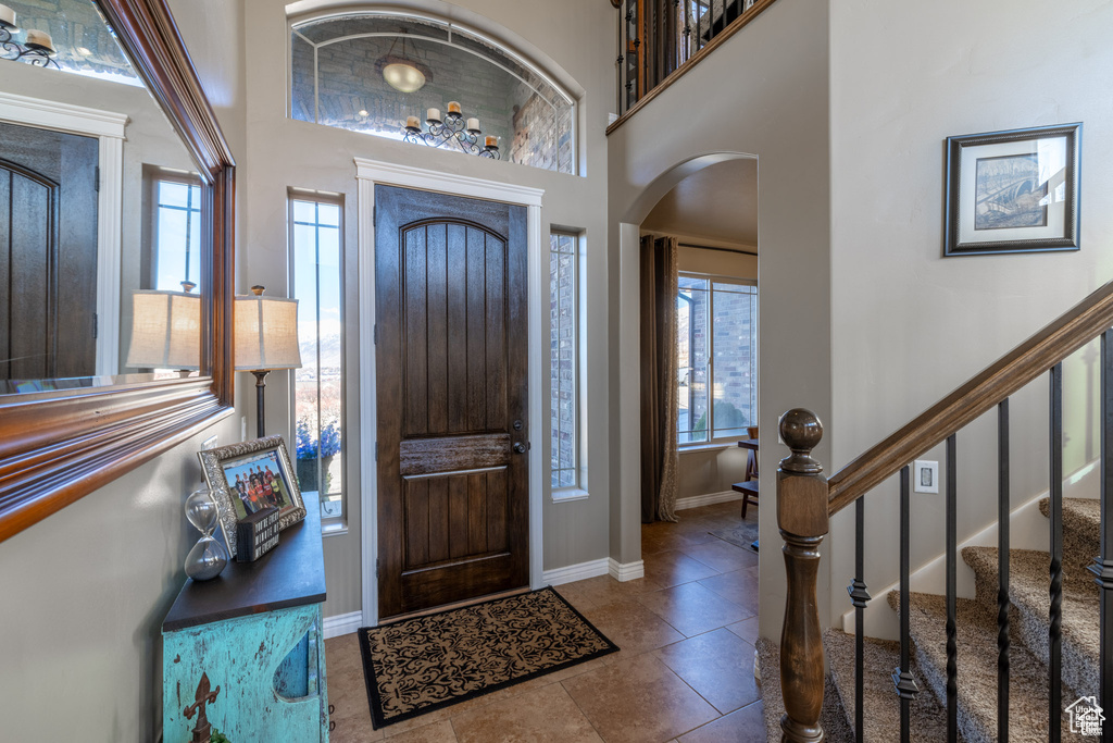 Tiled entrance foyer featuring arched walkways, a high ceiling, and stairway