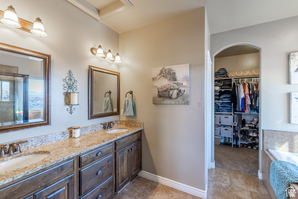 Bathroom with double vanity, a spacious closet, a tub, tile patterned floors, and a shower with shower door