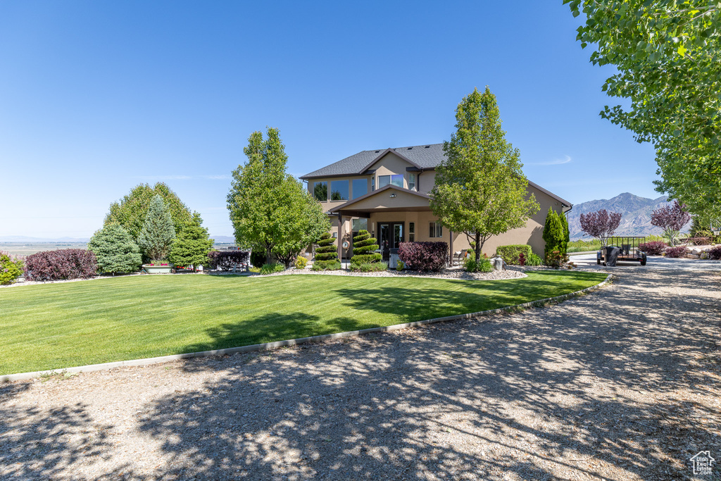 View of front of house featuring a front lawn, a mountain view, and stucco siding