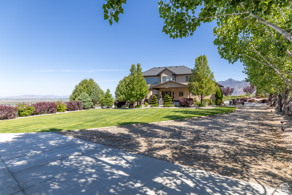 View of front of house featuring a front lawn, stucco siding, and a mountain view