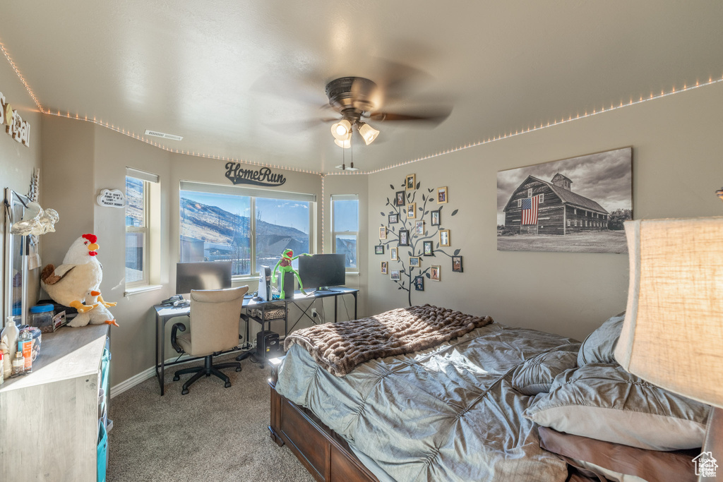 Carpeted bedroom featuring an office area and ceiling fan