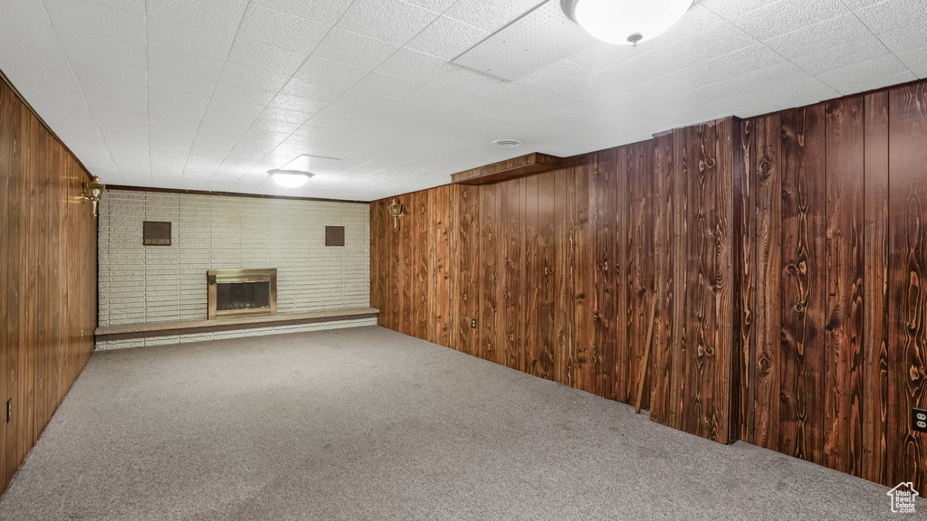 Finished basement with carpet flooring, wood walls, and a fireplace