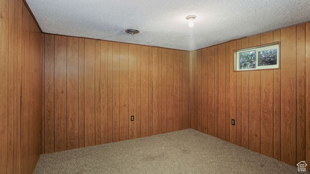Carpeted spare room with a textured ceiling and wood walls