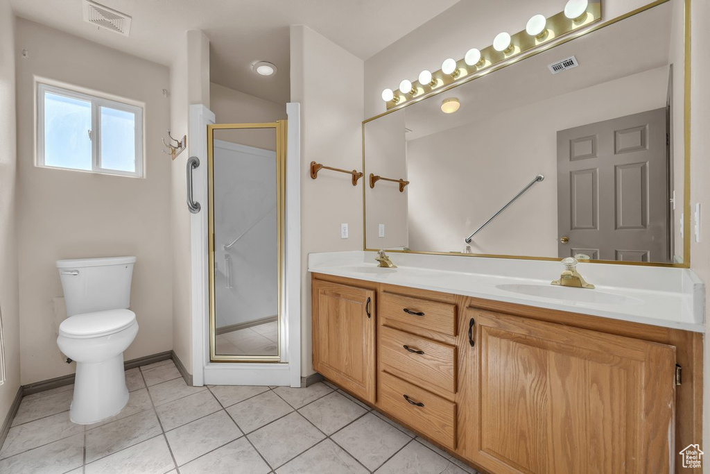 Bathroom featuring double vanity, a stall shower, and tile patterned floors