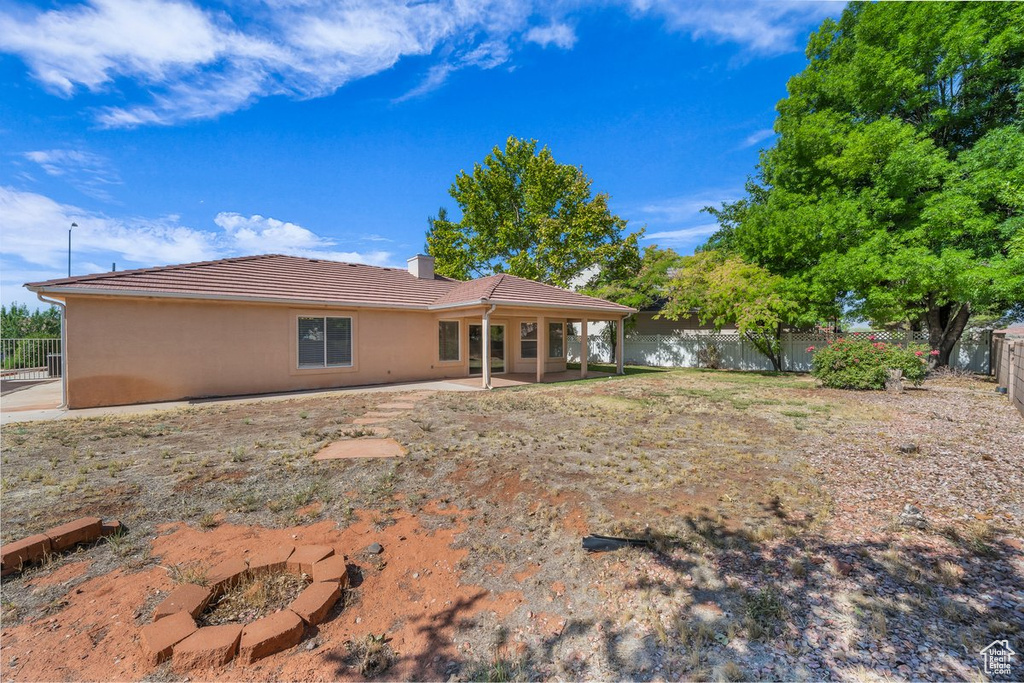 Rear view of house with a tile roof, a fenced backyard, a chimney, a patio area, and stucco siding