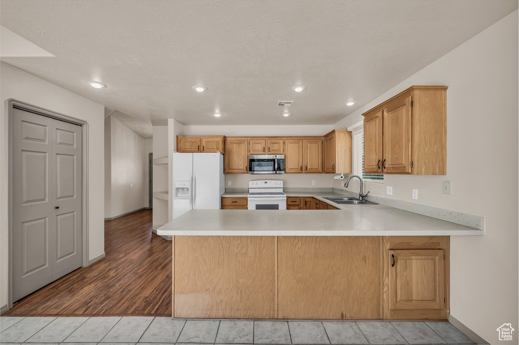 Kitchen with white appliances, light countertops, a peninsula, recessed lighting, and light tile patterned floors