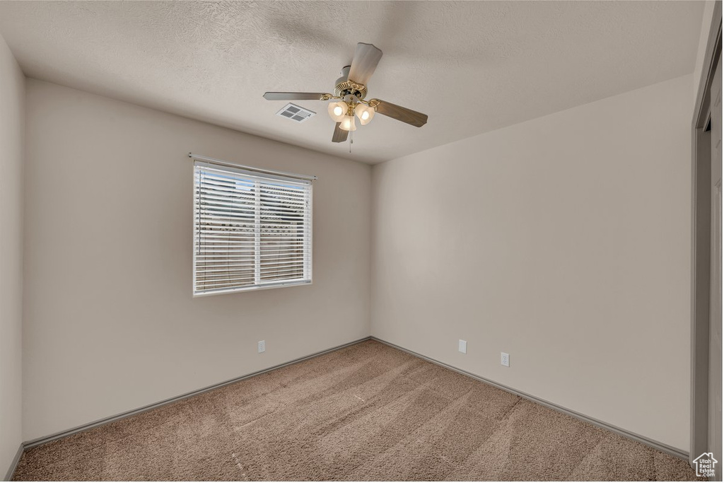 Carpeted spare room featuring a ceiling fan