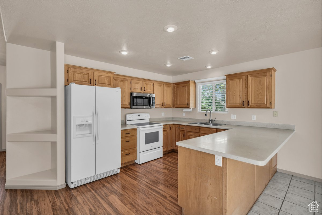 Kitchen with white appliances, a peninsula, light countertops, recessed lighting, and light wood-style floors