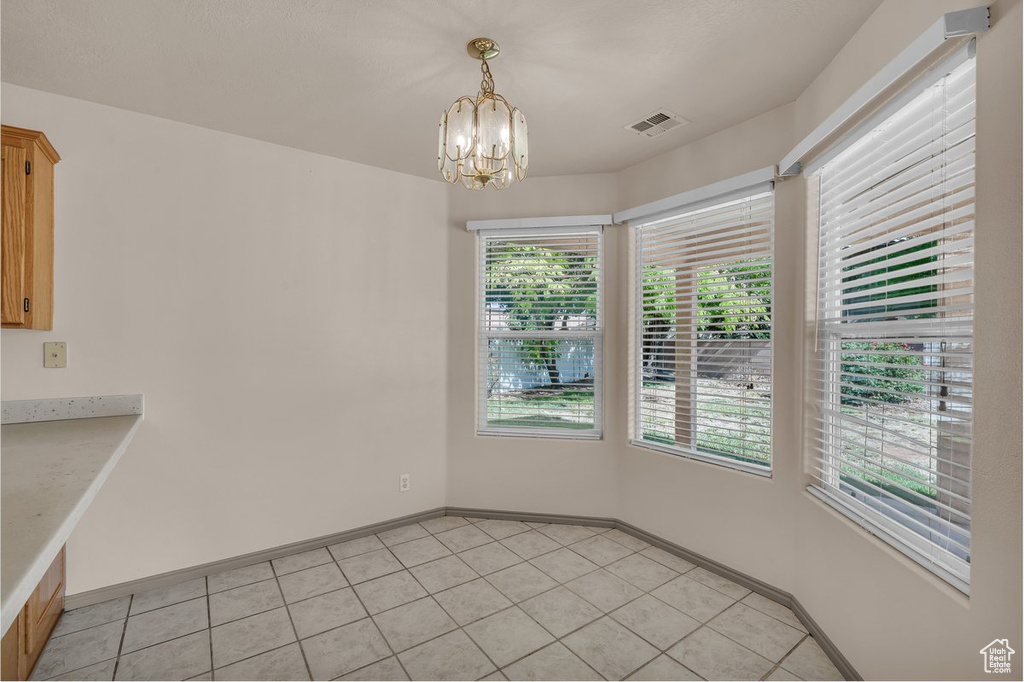 Unfurnished dining area with plenty of natural light, a chandelier, and light tile patterned flooring