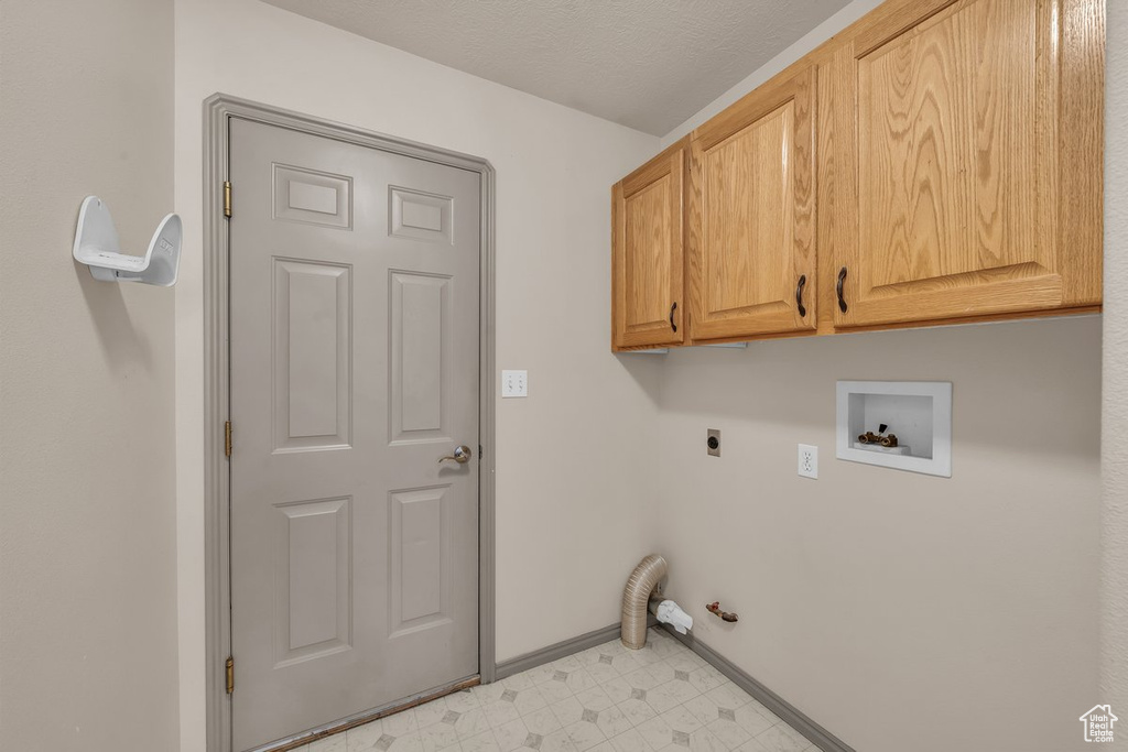 Washroom with washer hookup, cabinet space, electric dryer hookup, and light floors