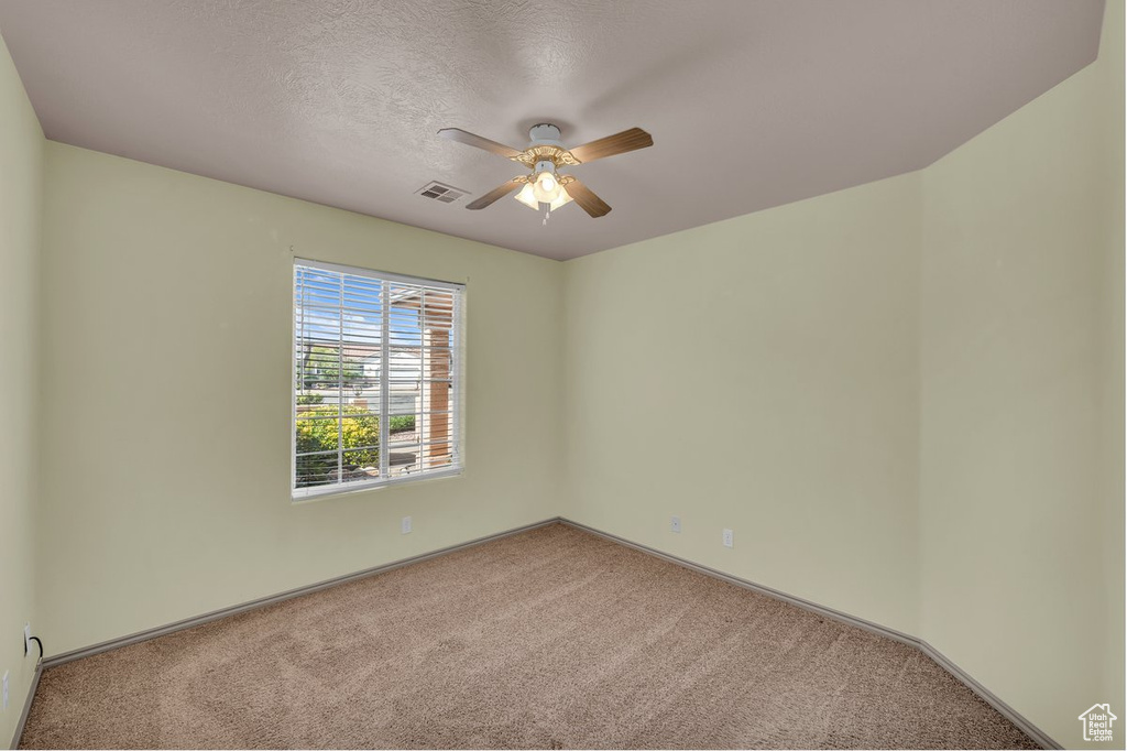 Spare room with carpet floors, a ceiling fan, and a textured ceiling
