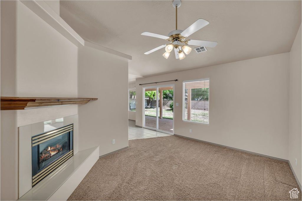 Unfurnished living room with carpet, ceiling fan, and a glass covered fireplace