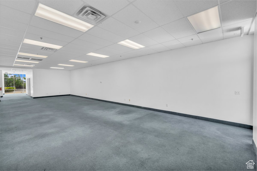 Carpeted spare room with baseboards and a drop ceiling