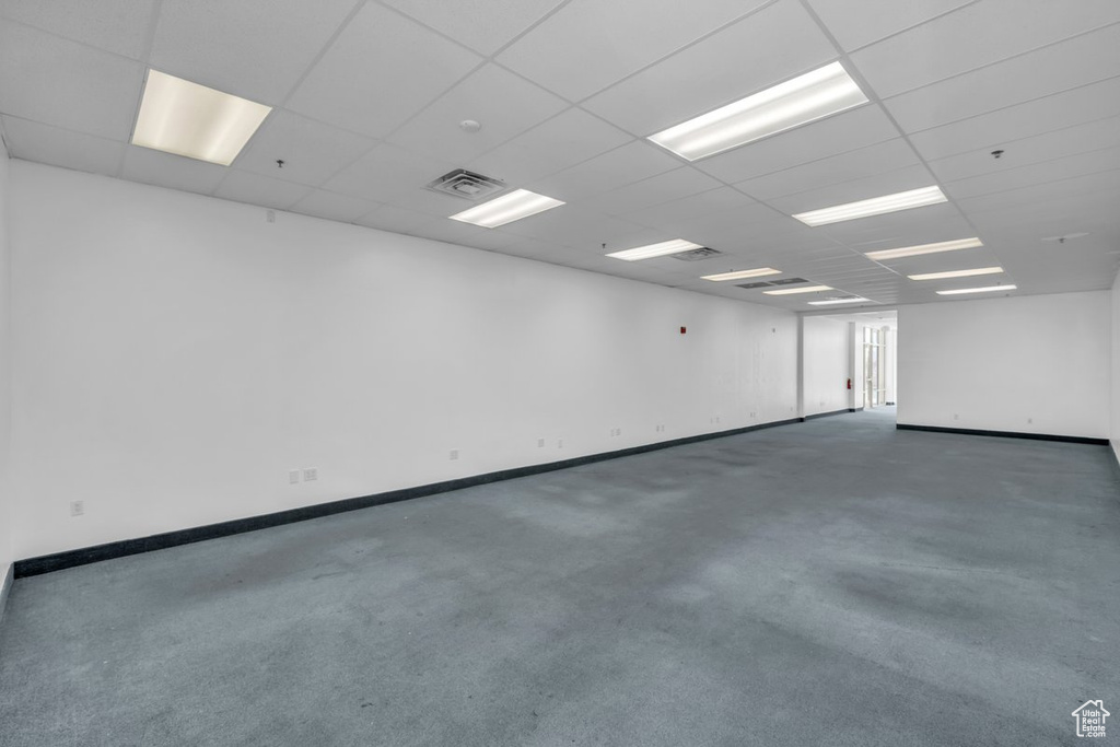 Spare room featuring carpet flooring, a drop ceiling, and fire sprinkler in ceiling