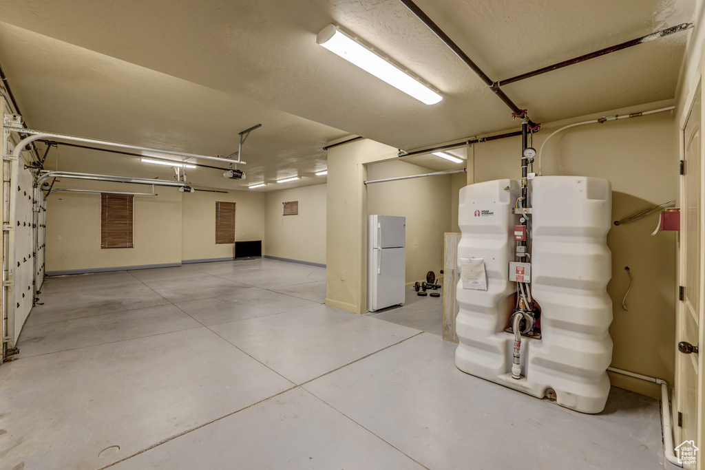Garage with freestanding refrigerator and baseboards