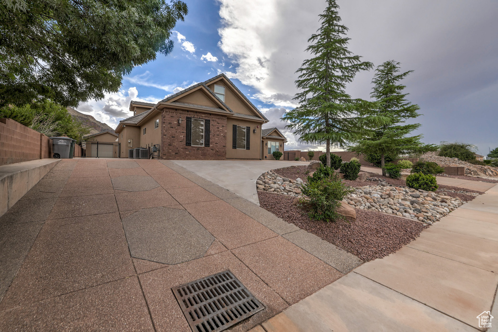 Ranch-style house with stucco siding, a gate, and brick siding