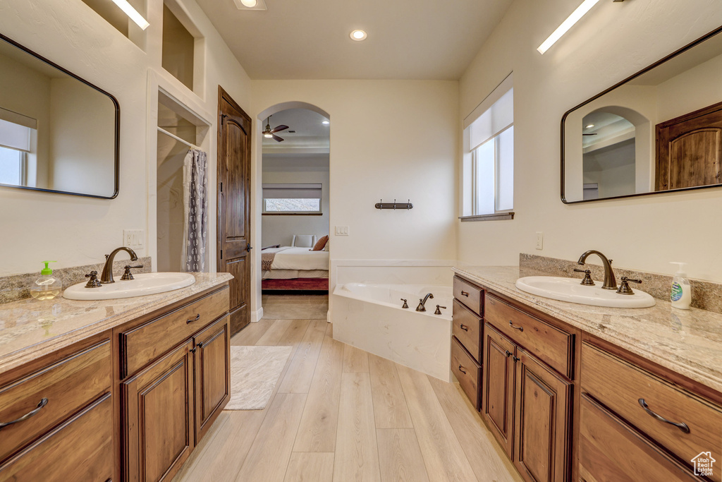 Ensuite bathroom with wood finished floors, a garden tub, two vanities, a shower with shower curtain, and recessed lighting