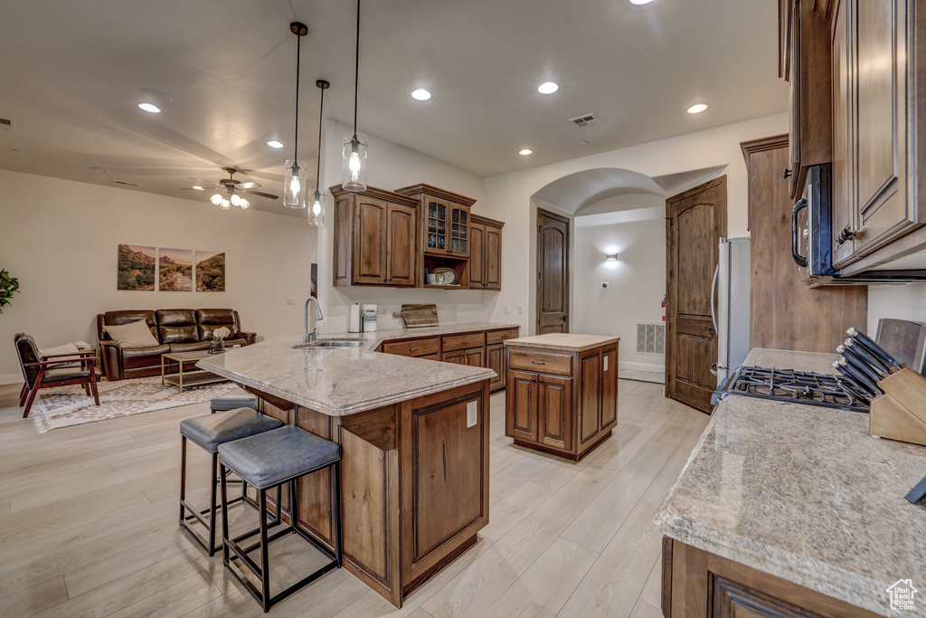 Kitchen featuring stainless steel appliances, arched walkways, a peninsula, a breakfast bar area, and a ceiling fan