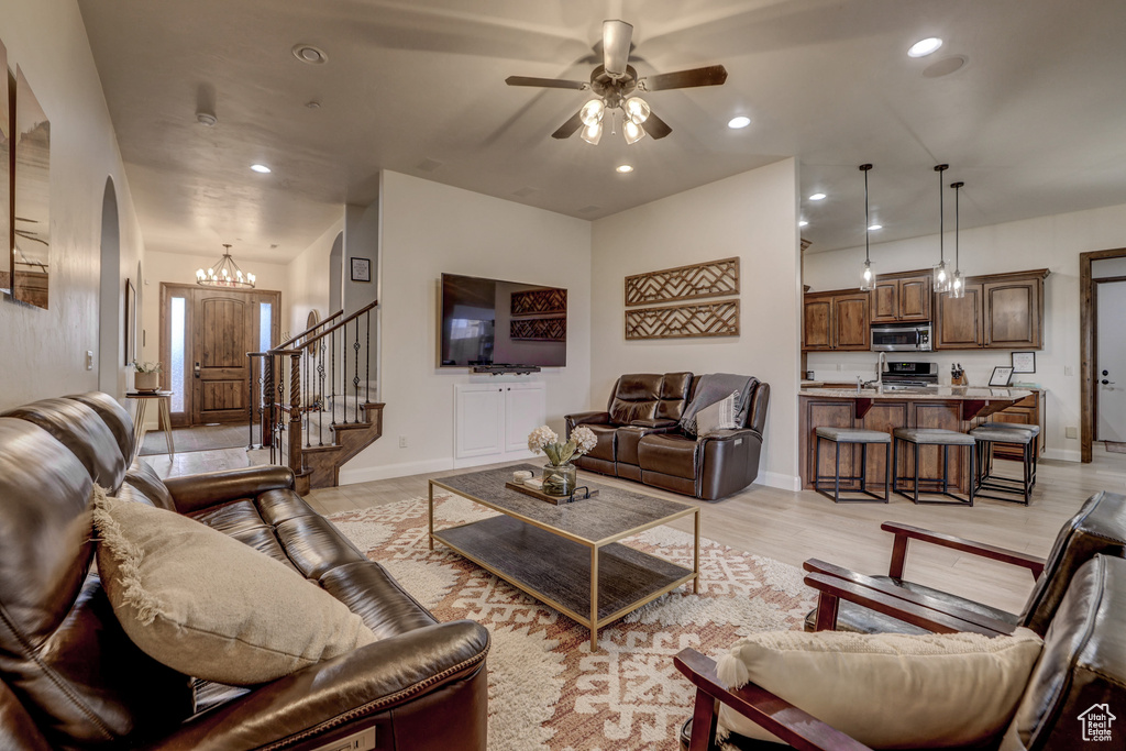 Living area featuring a ceiling fan, light wood-style flooring, recessed lighting, stairway, and arched walkways