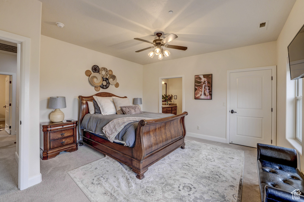 Bedroom featuring light colored carpet, ensuite bath, and ceiling fan