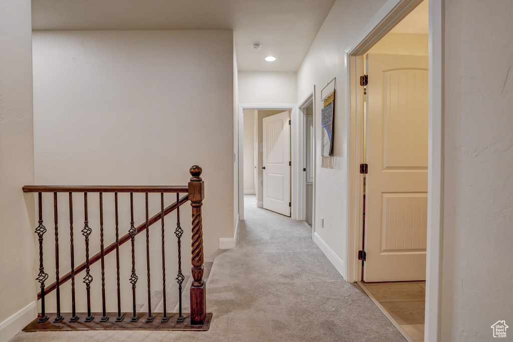 Hallway with an upstairs landing, carpet flooring, and recessed lighting