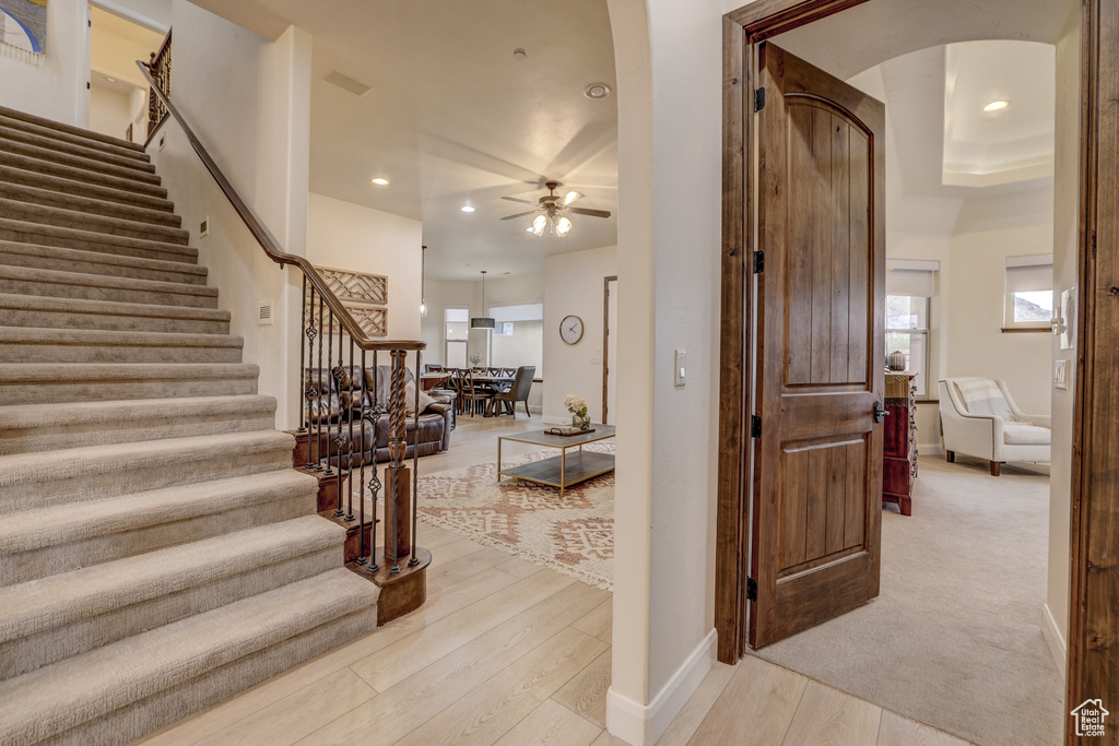Staircase featuring arched walkways, a ceiling fan, wood finished floors, recessed lighting, and plenty of natural light