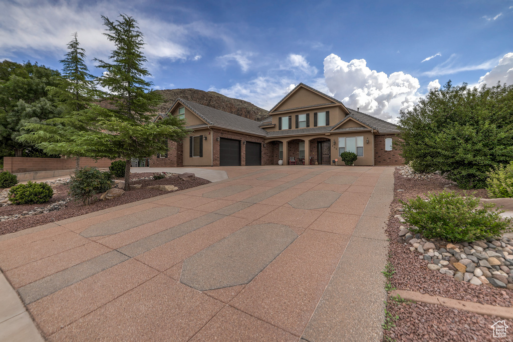 Traditional-style home with a garage, concrete driveway, brick siding, and stucco siding